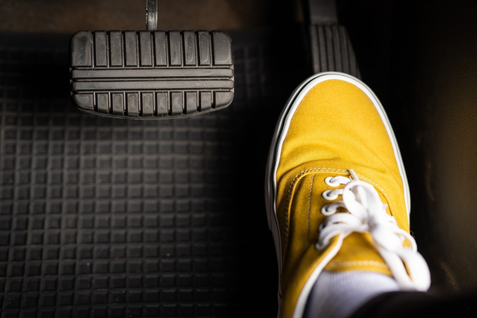 A man in yellow sneakers is stepping on the accelerator of a car Norton`s Car Clinic